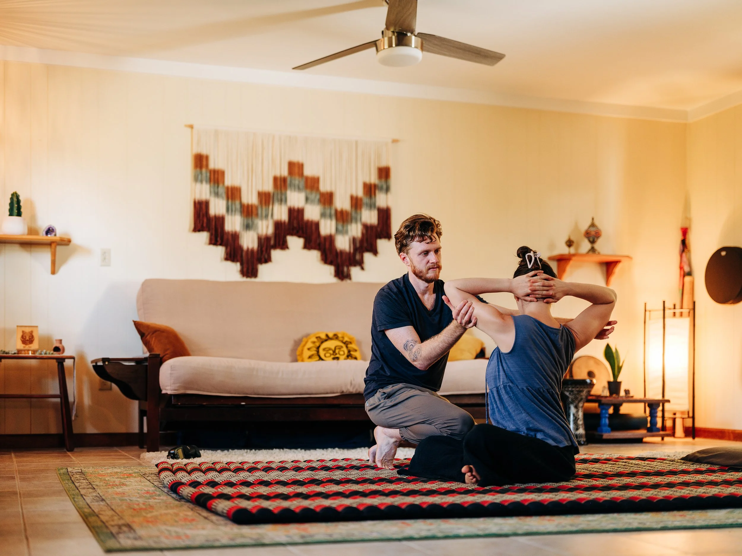Traditional Thai massage stretch on floor mat at Zen Fox Healing Arts studio in West Asheville NC